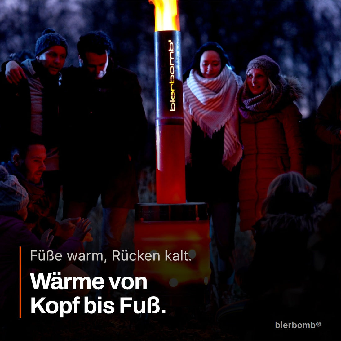 Gruppe in der Dämmerung um die brennende bierbomb® – die Wärme kommt von Kopf bis Fuß an