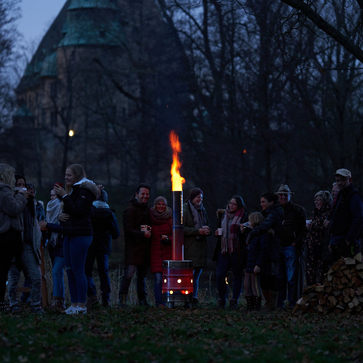 Gaeste stehen in der blauen Stunde um die brennende bierbomb und ruecken zusammen